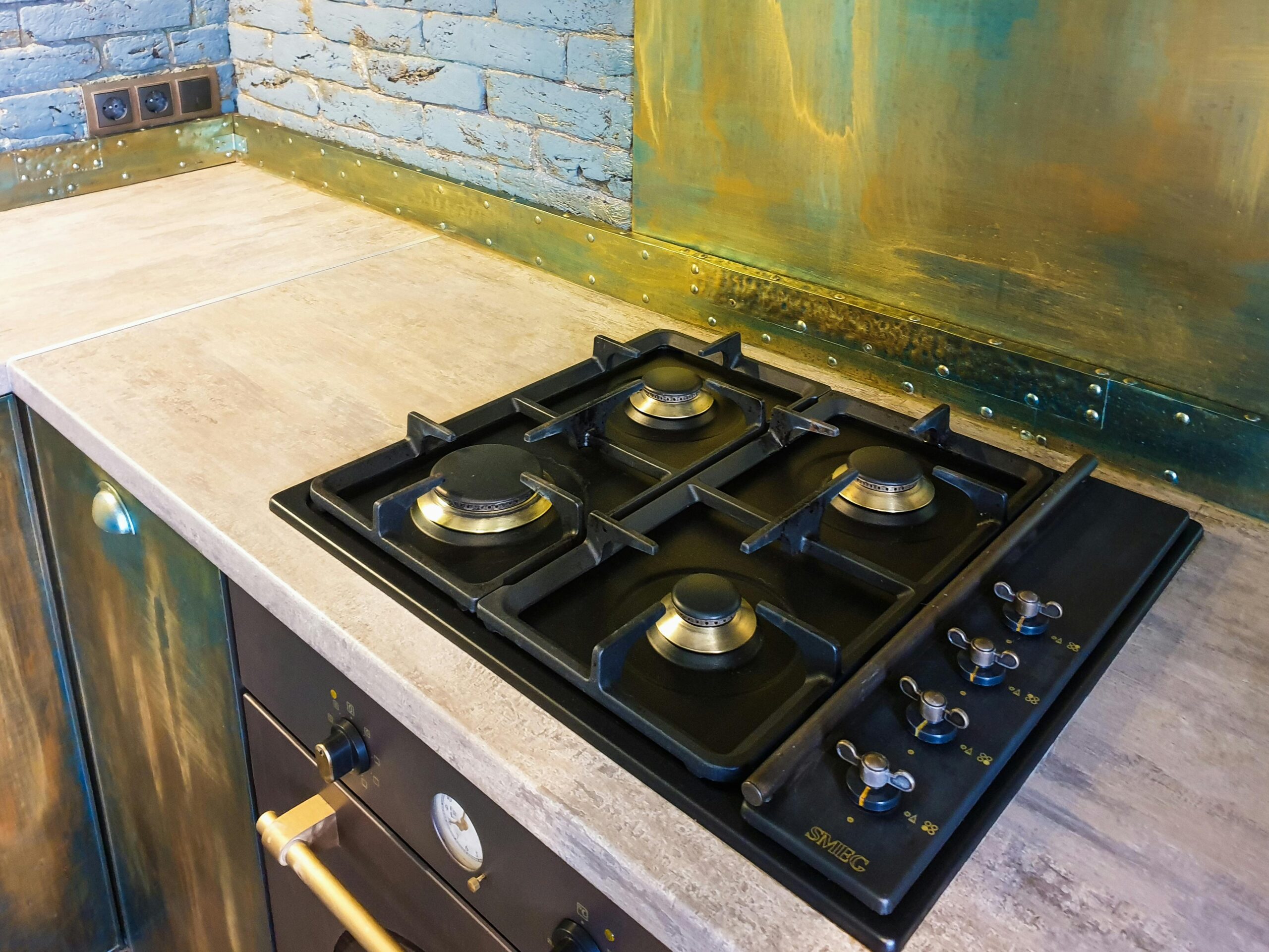 Close-up of a sleek modern gas stove on a rustic industrial style kitchen counter.